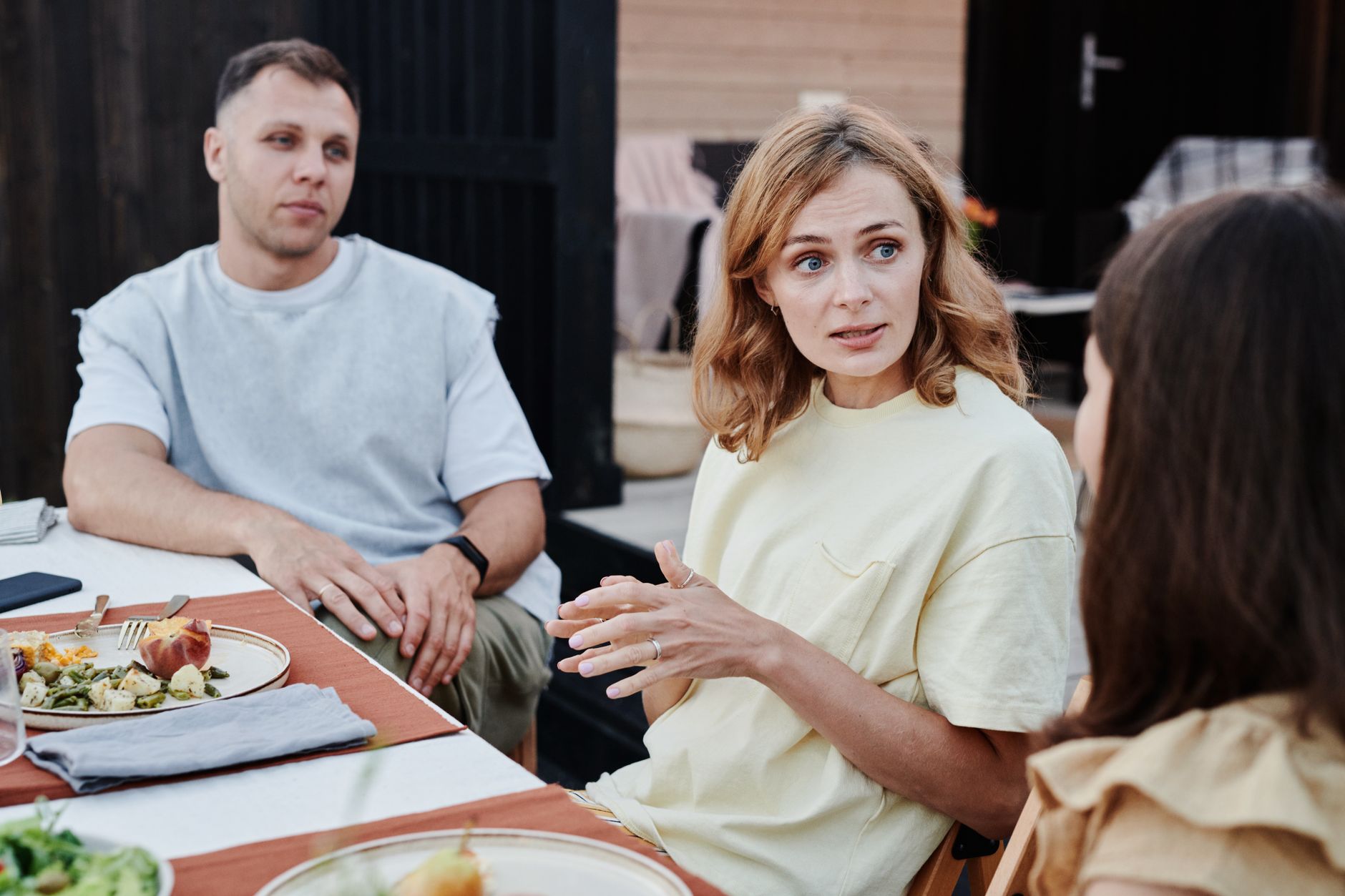 Volwassenen zitten samen buiten aan tafel tijdens een familiemaaltijd