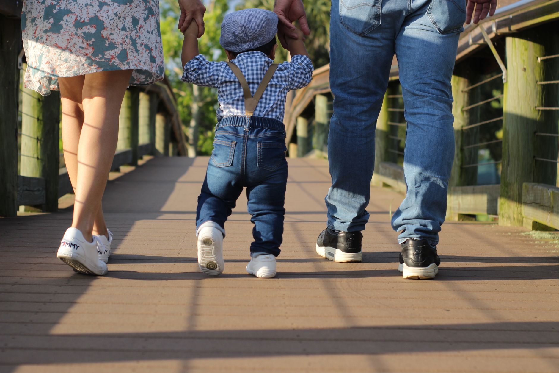 Ouders lopen hand in hand met hun kind tussen hen in, van achteren gezien