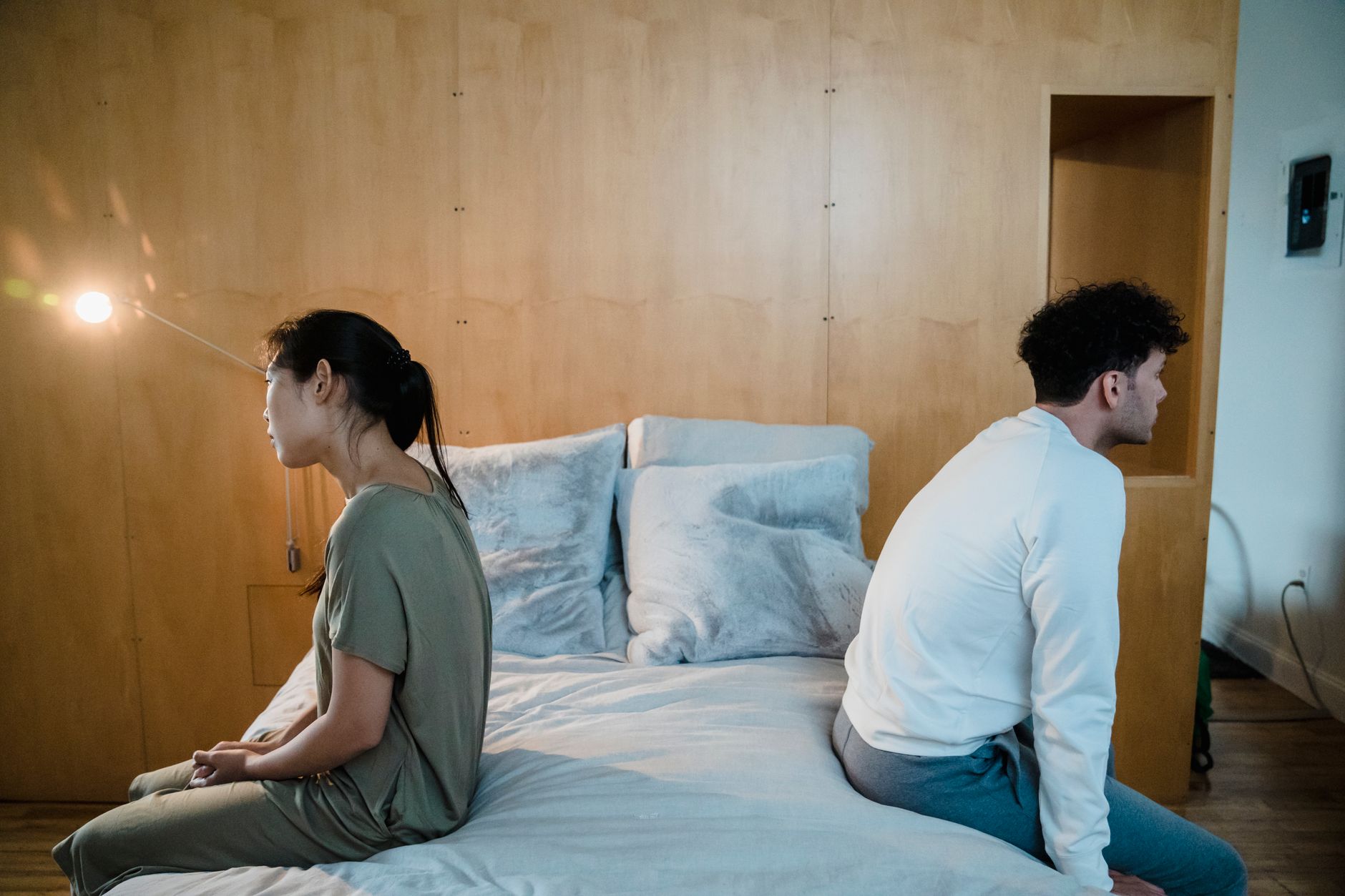 Man en vrouw zitten elk aan een kant van het bed met de rug naar elkaar toe