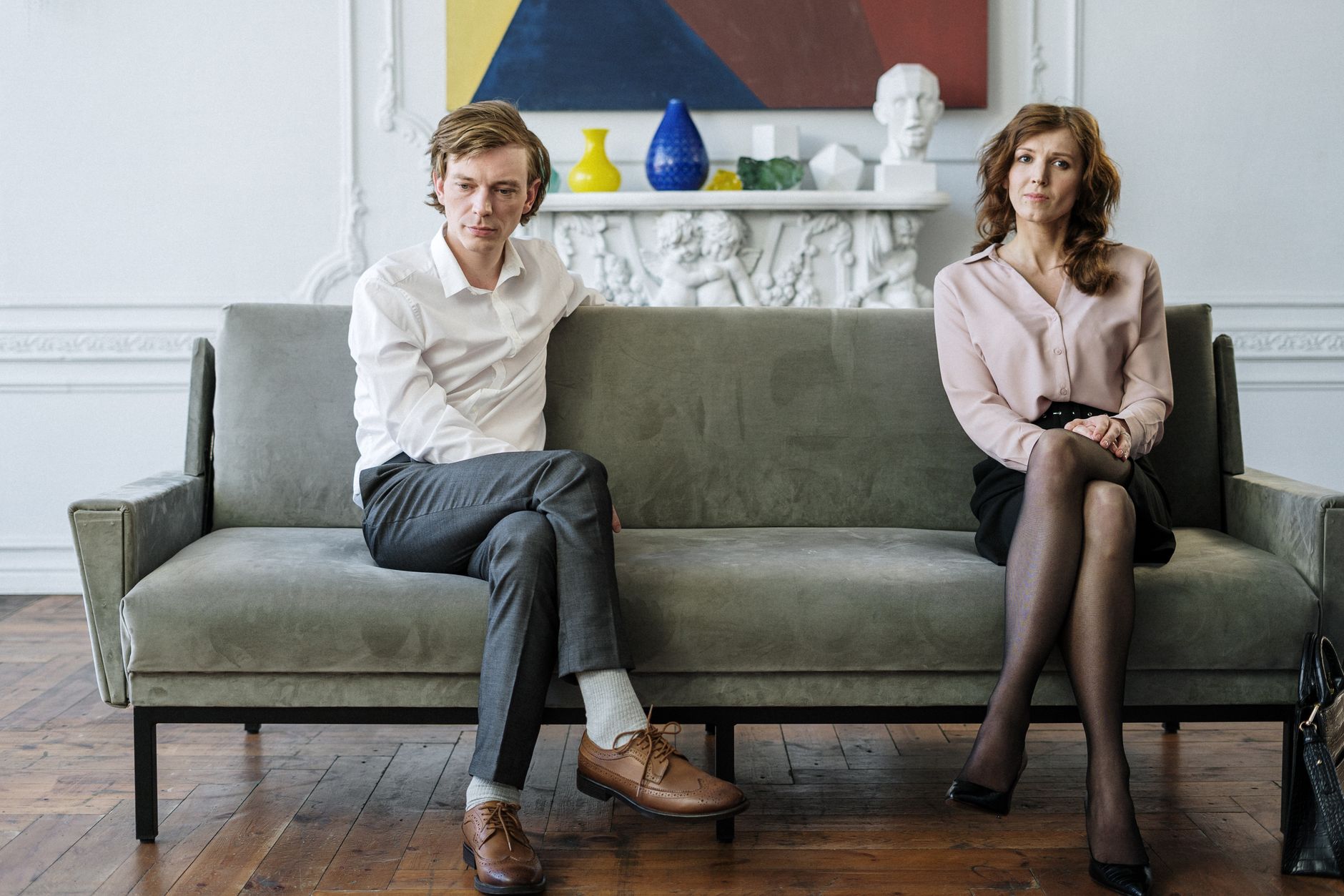 Man en vrouw zitten zwijgend aan weerszijden van een groene bank